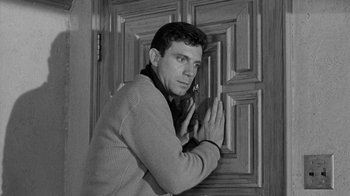 Movie still from “Period of Adjustment” (1962), directed by George Roy Hill – A black - and - white photo of a man standing in front of a door; Medium shot, Low angle