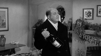 Movie still from “Period of Adjustment” (1962), directed by George Roy Hill – A black and white photo of a man holding a bottle of champagne; Medium shot, Over the shoulder angle
