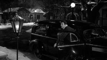 Movie still from “Period of Adjustment” (1962), directed by George Roy Hill – A black and white photo of a man driving a car; Wide shot, High angle