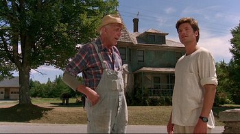 Movie still from “Pet Sematary” (1989), directed by Mary Lambert – A man standing next to another man in front of a house; Medium shot, Low angle