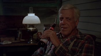 Movie still from “Pet Sematary” (1989), directed by Mary Lambert – An older man holding a bottle of beer in his hand; Close Up shot, Over the shoulder angle