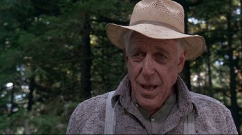 Movie still from “Pet Sematary” (1989), directed by Mary Lambert – An older man wearing a straw hat in a wooded area; Close Up shot, Low angle