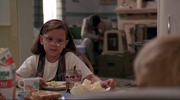 Movie still from “Pet Sematary” (1989), directed by Mary Lambert – A little girl sitting at a table eating a sandwich; Medium shot, Over the shoulder angle