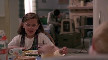 Movie still from “Pet Sematary” (1989), directed by Mary Lambert – A young girl sitting at a table with a glass; Medium shot, Over the shoulder angle