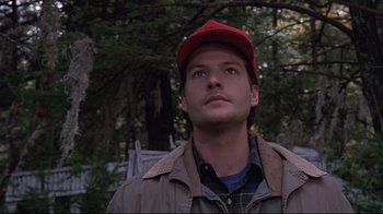 Movie still from “Pet Sematary” (1989), directed by Mary Lambert – A man with a red hat looking up at the sky; Close Up shot, Low angle