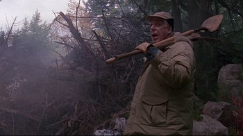 Movie still from “Pet Sematary” (1989), directed by Mary Lambert – An old man holding a stick in the woods; Medium shot, Low angle