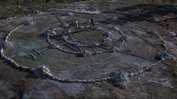 Movie still from “Pet Sematary” (1989), directed by Mary Lambert – A man standing in the middle of a circle of rocks; Extreme Wide shot, Overhead angle