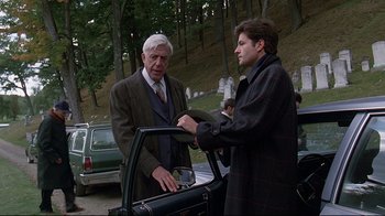 Movie still from “Pet Sematary” (1989), directed by Mary Lambert – Two men standing next to each other in front of a car; Medium shot, Over the shoulder angle