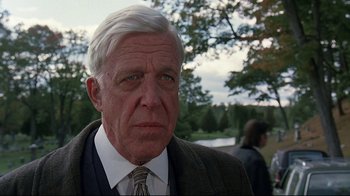 Movie still from “Pet Sematary” (1989), directed by Mary Lambert – An older man wearing a suit and a tie; Close Up shot, Over the shoulder angle