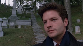 Movie still from “Pet Sematary” (1989), directed by Mary Lambert – A man in a suit standing in front of a grave yard; Close Up shot, Low angle