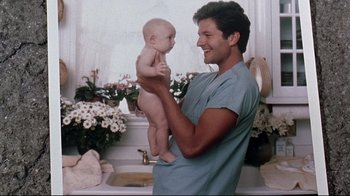 Movie still from “Pet Sematary” (1989), directed by Mary Lambert – A man holding a baby in his arms in a bathroom; Medium shot, Over the shoulder angle