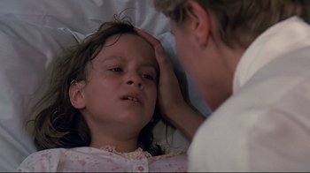 Movie still from “Pet Sematary” (1989), directed by Mary Lambert – A young girl laying in a bed with an adult; Close Up shot, High angle