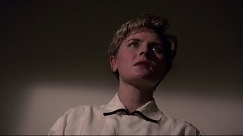 Movie still from “Pet Sematary” (1989), directed by Mary Lambert – A woman with short blonde hair wearing a white shirt; Close Up shot, Low angle