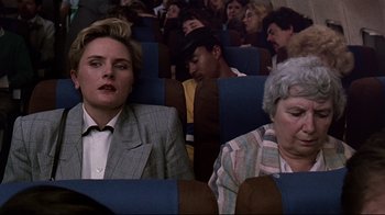 Movie still from “Pet Sematary” (1989), directed by Mary Lambert – Two people sitting in a row of seats; Medium shot, High angle