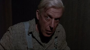 Movie still from “Pet Sematary” (1989), directed by Mary Lambert – An older man wearing a pair of suspenders stares at the camera; Close Up shot, Low angle