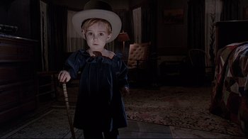 Movie still from “Pet Sematary” (1989), directed by Mary Lambert – A little boy wearing a top hat and holding a cane; Medium shot, High angle