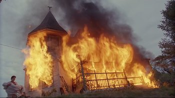 Movie still from “Pet Sematary” (1989), directed by Mary Lambert – A church is burning in the middle of the day; Extreme Wide shot, Low angle