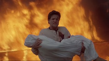 Movie still from “Pet Sematary” (1989), directed by Mary Lambert – A man holding a pillow in front of a fire background; Medium shot, Low angle