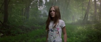 Movie still from “Pet Sematary” (2019), directed by Kevin Kölsch – A girl with long hair standing in the woods; Medium shot, Low angle