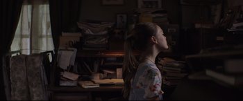 Movie still from “Pet Sematary” (2019), directed by Kevin Kölsch – A young girl standing in front of a cluttered desk; Medium shot, Over the shoulder angle