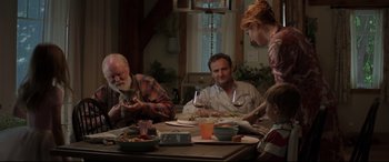 Movie still from “Pet Sematary” (2019), directed by Kevin Kölsch – A group of people sitting at a table with a cat; Medium shot, Over the shoulder angle