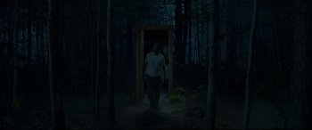 Movie still from “Pet Sematary” (2019), directed by Kevin Kölsch – A man walking in the woods near a door; Wide shot, High angle