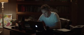 Movie still from “Pet Sematary” (2019), directed by Kevin Kölsch – A man sitting in front of an open laptop computer; Medium shot, Low angle