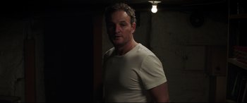 Movie still from “Pet Sematary” (2019), directed by Kevin Kölsch – A man in a white shirt standing in a dark room; Medium shot, Low angle