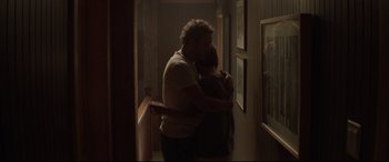 Movie still from “Pet Sematary” (2019), directed by Kevin Kölsch – A man and a woman hugging in a dark hallway; Medium shot, Over the shoulder angle