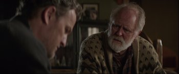 Movie still from “Pet Sematary” (2019), directed by Kevin Kölsch – A man sitting next to another man in a living room; Close Up shot, Over the shoulder angle