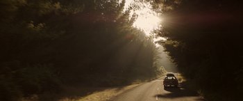 Movie still from “Pete's Dragon” (2016), directed by David Lowery – A car driving down a road near a wooded area; Extreme Wide shot, Low angle