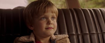 Movie still from “Pete's Dragon” (2016), directed by David Lowery – A little boy sitting in the back of a car; Close Up shot, Over the shoulder angle