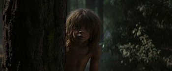 Movie still from “Pete's Dragon” (2016), directed by David Lowery – A young boy standing next to a tree in the woods; Close Up shot, Low angle