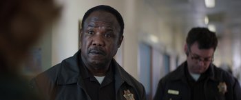 Movie still from “Pete's Dragon” (2016), directed by David Lowery – A man in a police uniform is standing in a hallway; Close Up shot, Over the shoulder angle