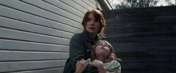 Movie still from “Pete's Dragon” (2016), directed by David Lowery – A woman holding a child in her arms outside; Medium shot, Low angle
