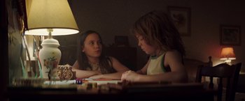 Movie still from “Pete's Dragon” (2016), directed by David Lowery – Two young girls sitting at a table playing a board game; Medium shot, Over the shoulder angle