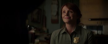Movie still from “Pete's Dragon” (2016), directed by David Lowery – A woman with a badge on her shirt is smiling; Close Up shot, Over the shoulder angle