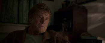 Movie still from “Pete's Dragon” (2016), directed by David Lowery – An older man sitting on a couch in a living room; Close Up shot, Over the shoulder angle