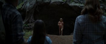 Movie still from “Pete's Dragon” (2016), directed by David Lowery – A young girl standing in front of an entrance to a cave; Wide shot, High angle