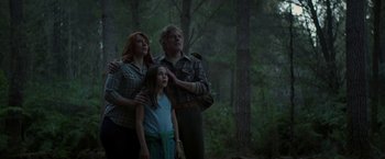 Movie still from “Pete's Dragon” (2016), directed by David Lowery – A man and a woman and a girl standing in the woods; Medium shot, Low angle