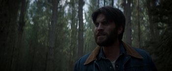 Movie still from “Pete's Dragon” (2016), directed by David Lowery – A man with long hair and a beard standing in the woods; Close Up shot, Low angle