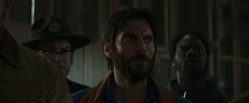 Movie still from “Pete's Dragon” (2016), directed by David Lowery – A man with long hair and a goatee stares into the distance; Close Up shot, Over the shoulder angle