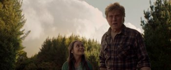 Movie still from “Pete's Dragon” (2016), directed by David Lowery – A man standing next to a woman in a field; Medium shot, Low angle