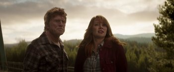Movie still from “Pete's Dragon” (2016), directed by David Lowery – A man and a woman standing next to each other in front of trees; Medium shot, Low angle