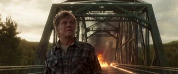 Movie still from “Pete's Dragon” (2016), directed by David Lowery – A man standing in front of a bridge with fire; Medium shot, Low angle
