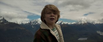 Movie still from “Pete's Dragon” (2016), directed by David Lowery – A young boy in a plaid jacket with mountains in the background; Close Up shot, Low angle