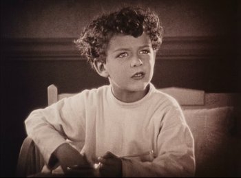 Movie still from “Peter Pan” (1924), directed by Herbert Brenon – A young boy with curly hair sitting in a chair; Close Up shot, High angle