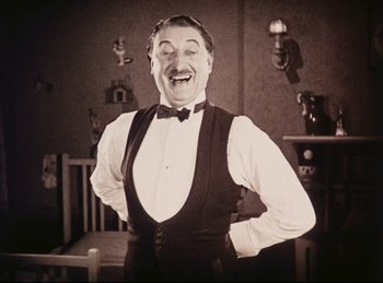 Movie still from “Peter Pan” (1924), directed by Herbert Brenon – An old photo of a man in a vest and a bow tie; Medium shot, Low angle