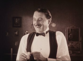 Movie still from “Peter Pan” (1924), directed by Herbert Brenon – An old photo of a man in a bow tie; Medium shot, Low angle