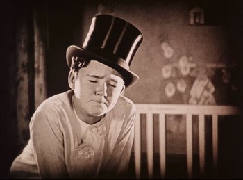 Movie still from “Peter Pan” (1924), directed by Herbert Brenon – A young man wearing a top hat sitting on a chair; Medium shot, Low angle